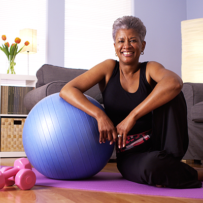In black fitness clothes, an elderly woman poses with the exercise balance ball