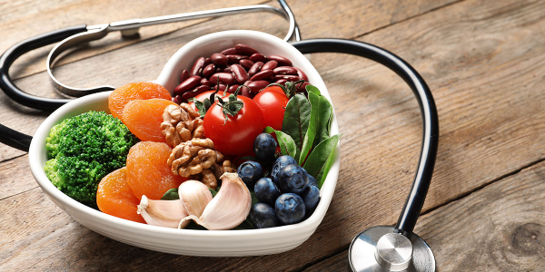 A heart-shaped bowl loaded with nuts, fruits and vegetables for a healthy heart.
