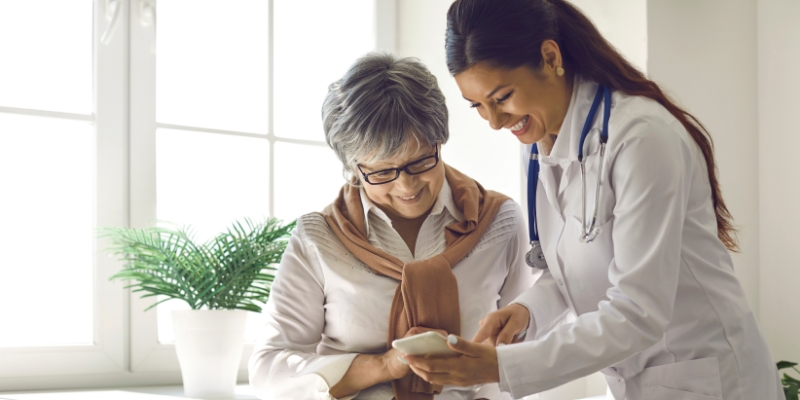 female healthcare taker helping an elderly woman with a mobile health app